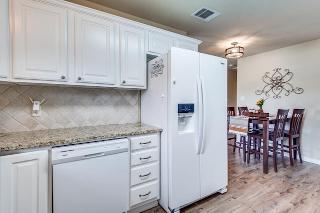 kitchen with light hardwood / wood-style flooring, white appliances, light stone counters, white cabinets, and decorative backsplash