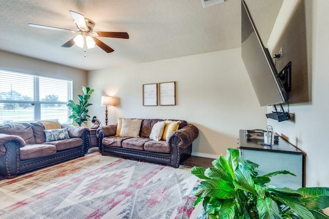 living room with a textured ceiling, hardwood / wood-style flooring, and ceiling fan