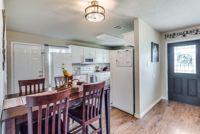 dining space featuring a wealth of natural light, a textured ceiling, and light hardwood / wood-style flooring