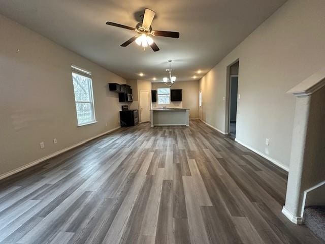 unfurnished living room featuring dark hardwood / wood-style floors and ceiling fan with notable chandelier