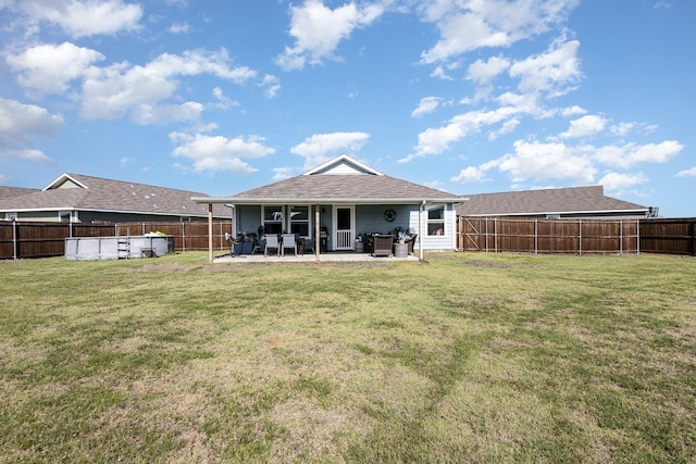 rear view of property featuring a yard, a patio area, and a fenced backyard