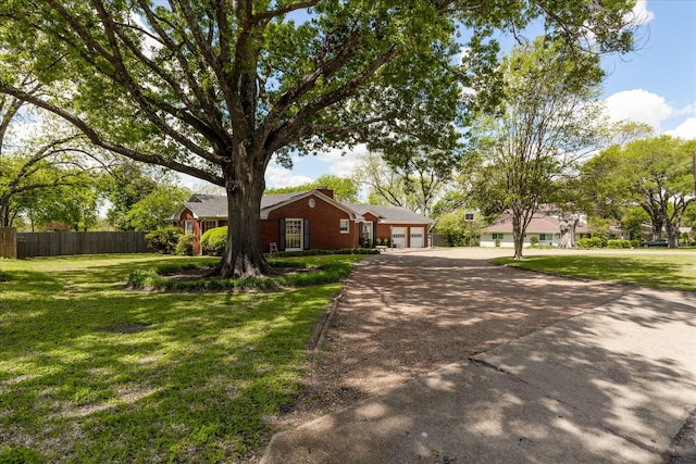 ranch-style home featuring a garage, driveway, a front lawn, and fence