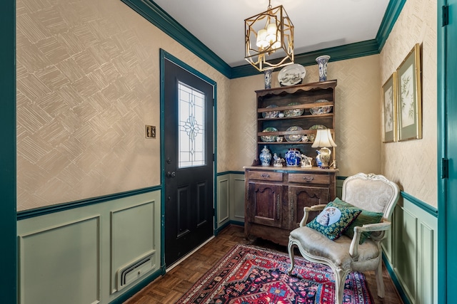 entrance foyer with a chandelier, crown molding, and dark parquet flooring