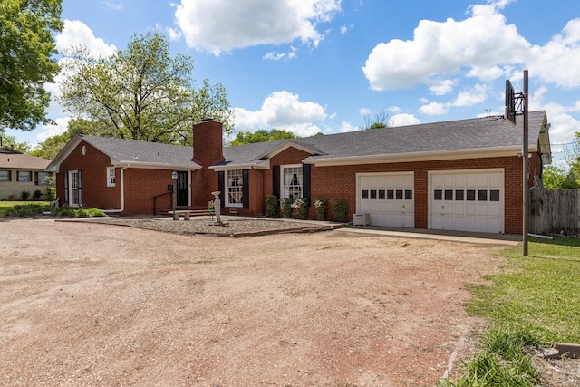 single story home with driveway, brick siding, a chimney, and an attached garage