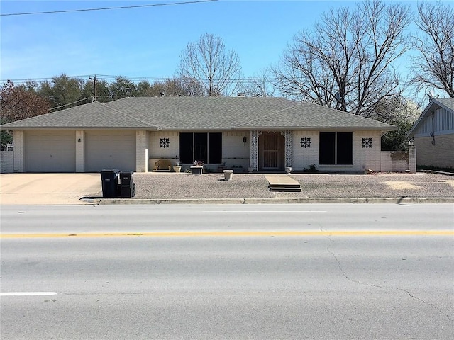 view of front of property featuring driveway, brick siding, roof with shingles, and an attached garage