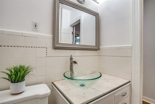 bathroom with toilet, tile walls, and vanity