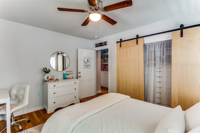 bedroom featuring hardwood / wood-style flooring, ceiling fan, and a barn door