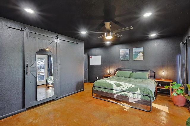 bedroom featuring concrete flooring, ceiling fan, and a barn door