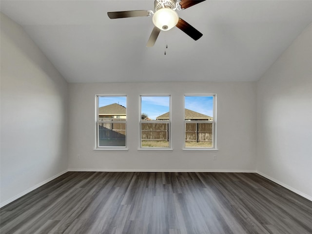 empty room featuring lofted ceiling, dark wood-style flooring, and baseboards