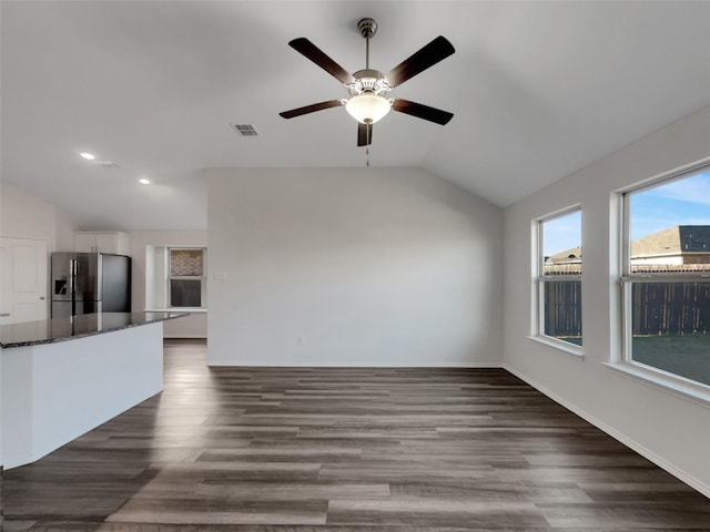 unfurnished living room with baseboards, visible vents, dark wood finished floors, ceiling fan, and vaulted ceiling