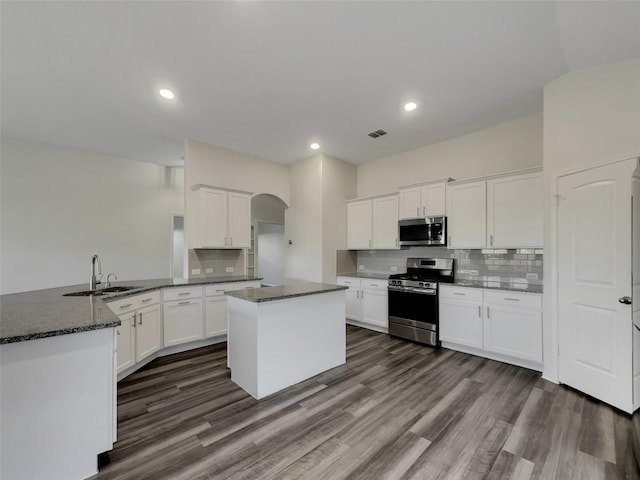 kitchen with visible vents, arched walkways, a peninsula, stainless steel appliances, and white cabinetry