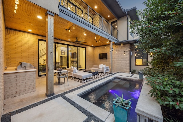 view of swimming pool with ceiling fan, a patio, exterior kitchen, and an outdoor living space