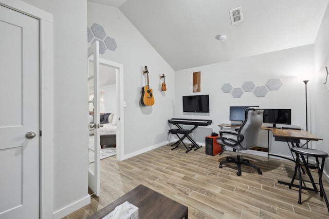 office featuring light wood-type flooring, visible vents, lofted ceiling, and baseboards