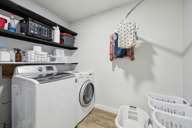 washroom featuring baseboards, laundry area, light wood finished floors, and washer and dryer