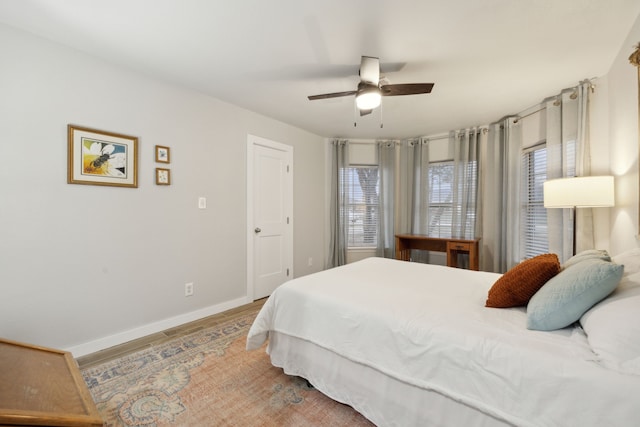 bedroom featuring a ceiling fan, baseboards, and wood finished floors