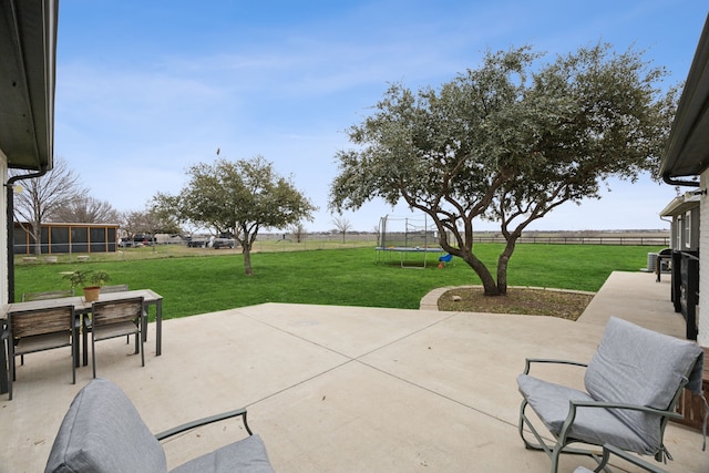 view of patio / terrace featuring a trampoline, fence, and outdoor dining space