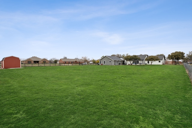 view of yard featuring a storage shed, a residential view, fence, and an outdoor structure