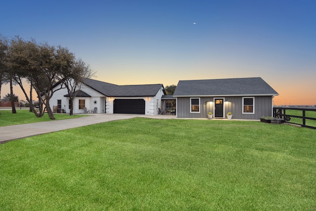 view of front facade featuring driveway, a front lawn, an attached garage, and fence