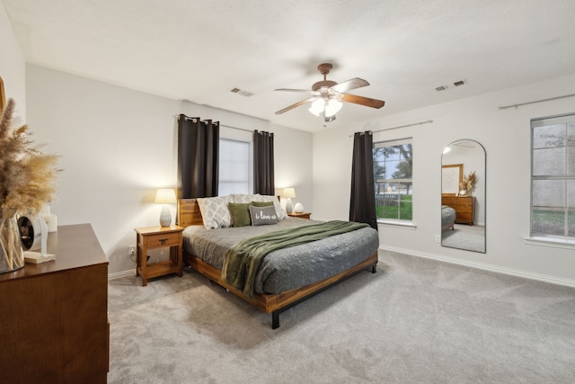 bedroom with baseboards, a ceiling fan, visible vents, and light colored carpet