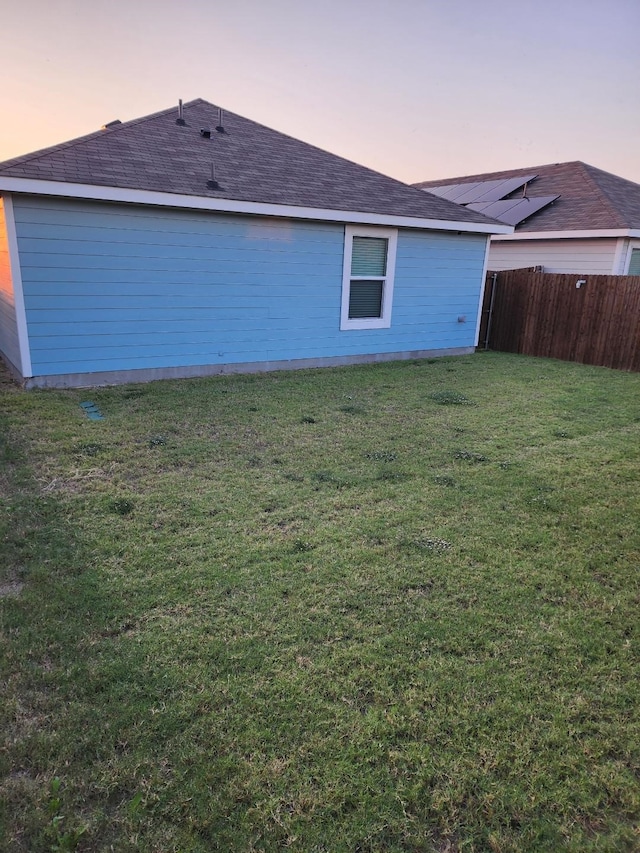 back house at dusk featuring a lawn