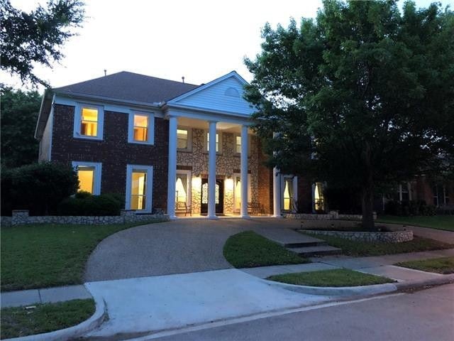 neoclassical home featuring a front lawn