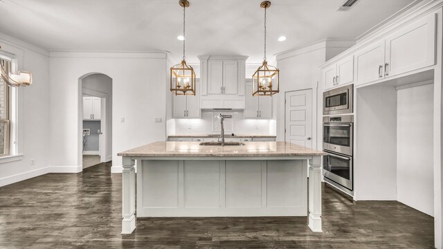 114 N Star Crossing Ln, Weatherford, TX 76088 - kitchen with light stone counters, dark wood finished floors, arched walkways, stainless steel appliances, and white cabinets