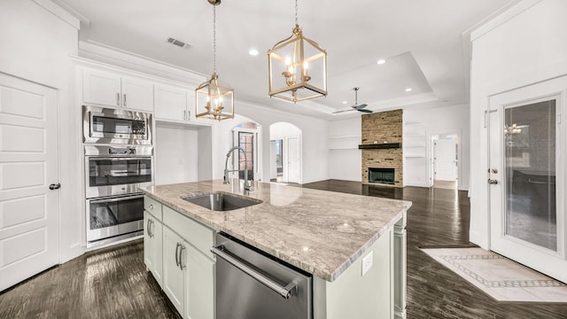 114 N Star Crossing Ln, Weatherford, TX 76088 - kitchen with a sink, stainless steel appliances, ceiling fan with notable chandelier, a large fireplace, and arched walkways