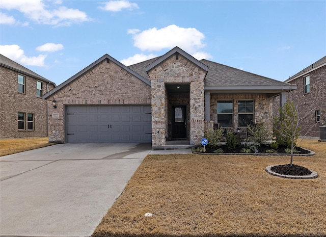 view of front of property featuring a front yard, a garage, and central air condition unit