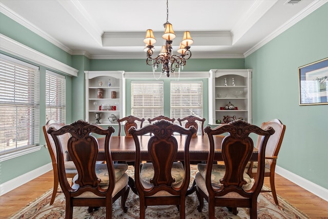 dining area with a tray ceiling, crown molding, an inviting chandelier, and hardwood / wood-style floors