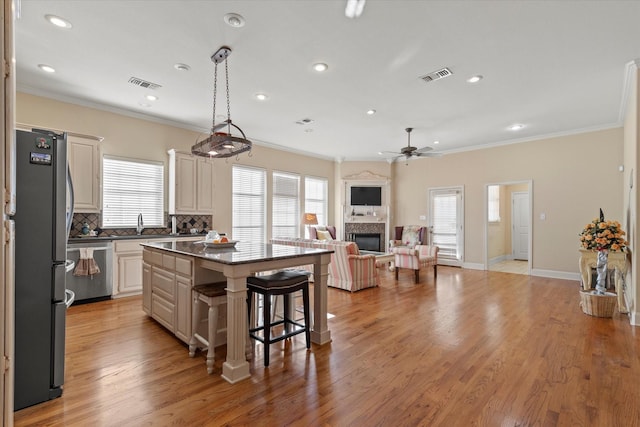 kitchen with light hardwood / wood-style flooring, backsplash, a kitchen island, stainless steel appliances, and a breakfast bar area