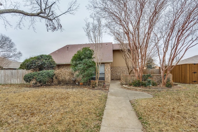 view of front of home featuring fence private yard, a shingled roof, a front lawn, and brick siding