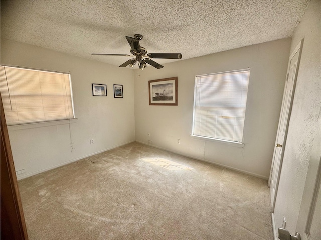 empty room with ceiling fan, a textured ceiling, and light colored carpet