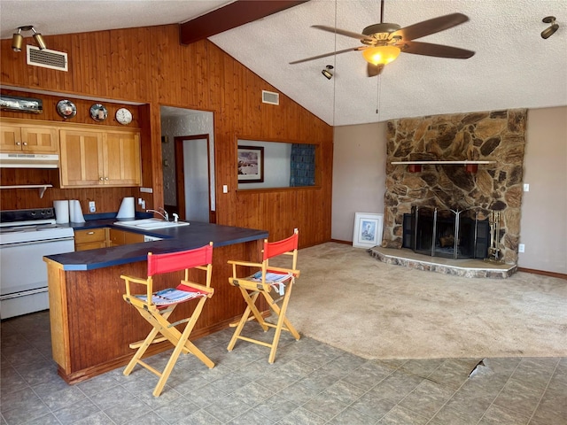 kitchen with electric range, carpet, kitchen peninsula, wooden walls, and a breakfast bar area