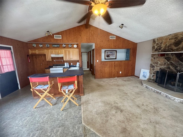 interior space with a fireplace, lofted ceiling with beams, wood walls, and a textured ceiling