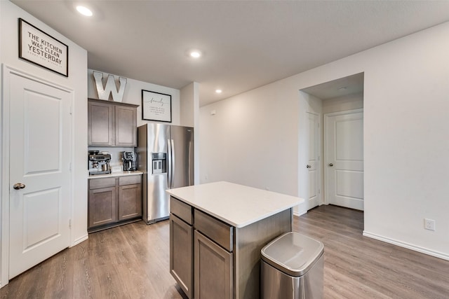 kitchen with hardwood / wood-style flooring, a center island, and stainless steel refrigerator with ice dispenser