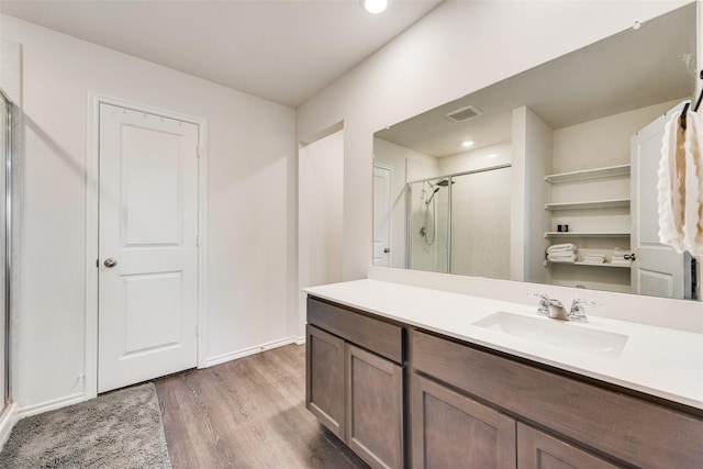 bathroom featuring hardwood / wood-style floors, a shower with shower door, and vanity