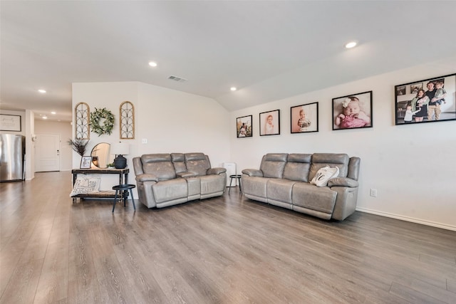 living room featuring vaulted ceiling and wood-type flooring