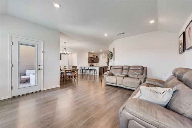 living room with vaulted ceiling, hardwood / wood-style floors, and a chandelier