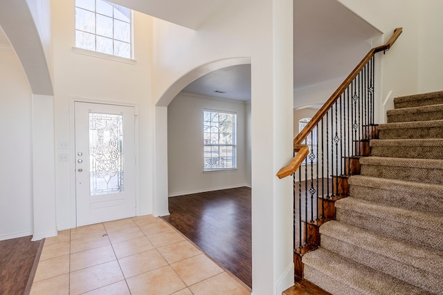 entrance foyer featuring ornamental molding, light tile patterned flooring, stairway, and baseboards