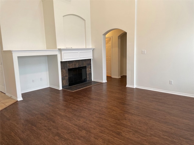 unfurnished living room featuring a tile fireplace and dark hardwood / wood-style floors