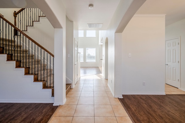 entrance foyer featuring arched walkways, light tile patterned flooring, visible vents, baseboards, and stairway