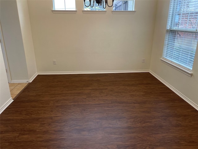 unfurnished room featuring dark hardwood / wood-style floors and an inviting chandelier