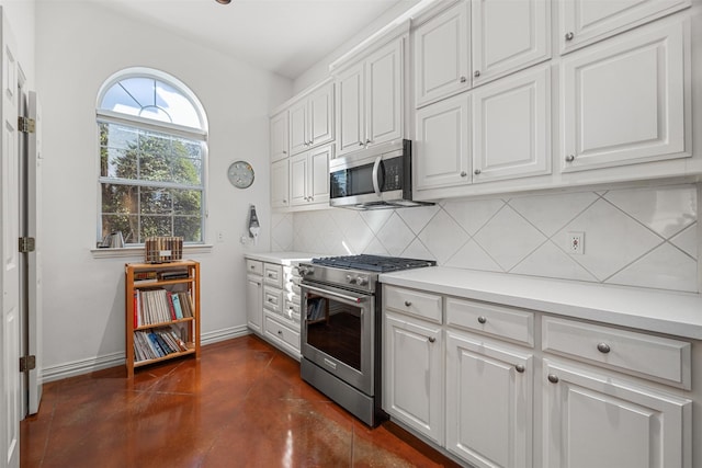 kitchen with appliances with stainless steel finishes, white cabinets, and tasteful backsplash