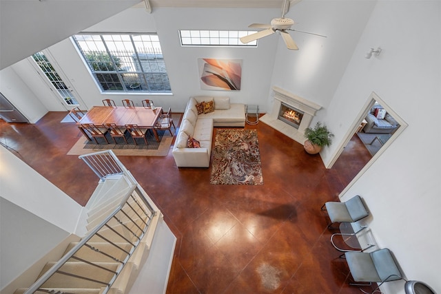 living room with ceiling fan and a towering ceiling