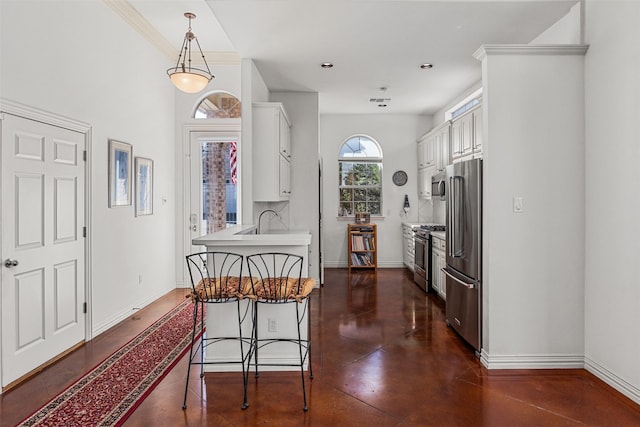 kitchen featuring a kitchen bar, pendant lighting, stainless steel appliances, white cabinets, and ornamental molding