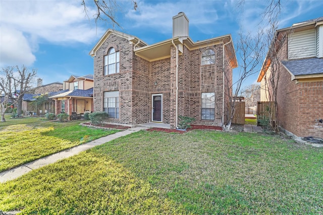 view of front of property featuring brick siding, a chimney, a front yard, and fence