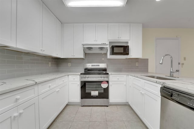 kitchen with appliances with stainless steel finishes, white cabinets, a sink, light tile patterned flooring, and under cabinet range hood