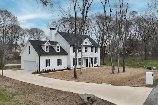 view of front facade featuring a shingled roof, a chimney, a balcony, a garage, and driveway