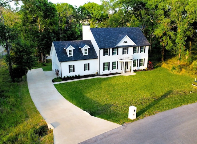 view of front of home with stucco siding, a porch, a chimney, and a front lawn