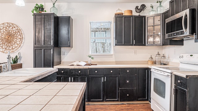 kitchen with hardwood / wood-style flooring, sink, electric stove, and tile countertops